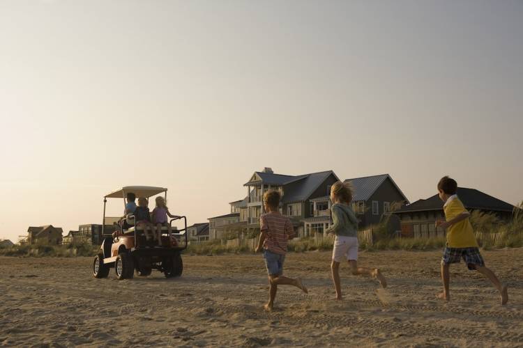 Kids chasing golf cart on the beach