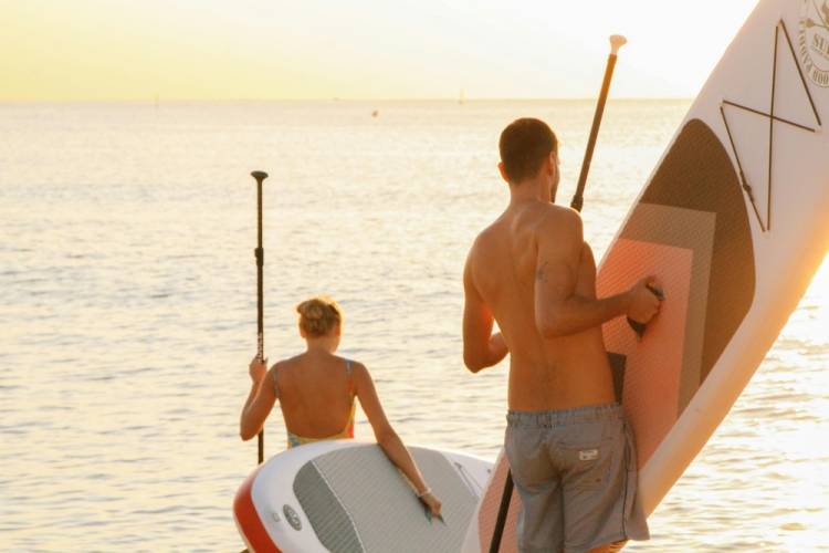 Friends hauling paddle board rentals to the beach